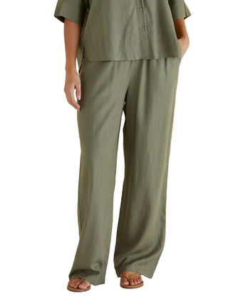 Person wearing a green outfit with wide-leg pants against a beige background