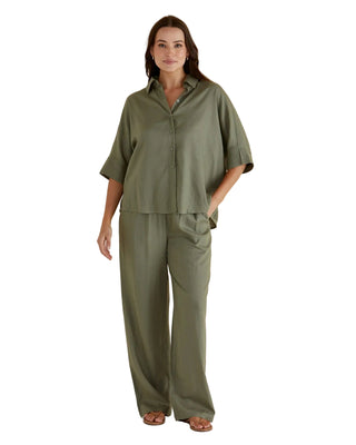 Woman wearing a green outfit against a beige background