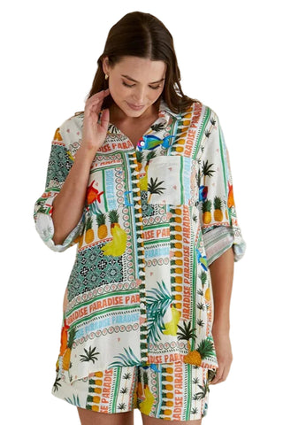 Woman wearing a colorful patterned dress with tropical designs on a beige background