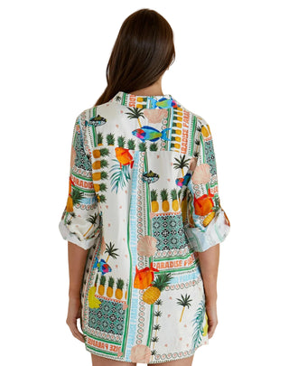 Woman wearing a colorful tropical print dress on a beige background