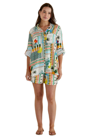 Woman wearing a colorful patterned dress against a beige background