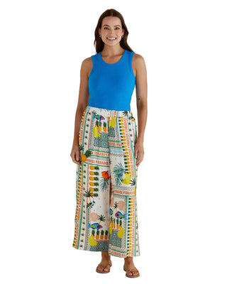 Woman wearing a blue sleeveless top and colorful patterned pants against a beige background