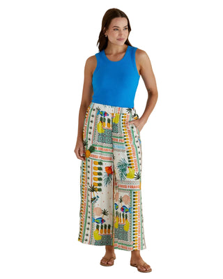 Woman wearing a blue top and colorful patterned pants against a beige background