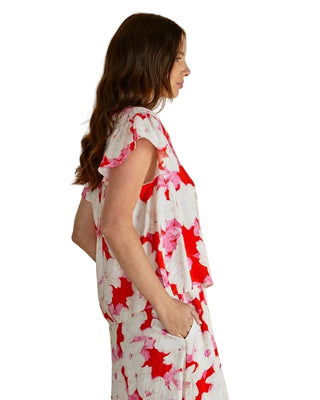 Woman wearing a floral dress with red and pink flowers on a beige background