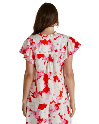 Woman wearing a red and white floral dress on a beige background