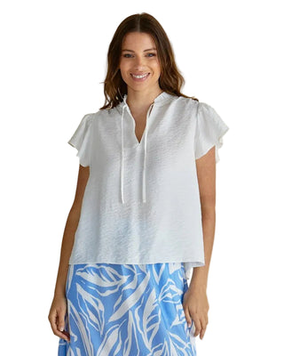 Woman wearing a white blouse with short sleeves and a blue and white patterned skirt on a beige background