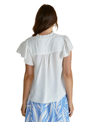 Woman wearing a white blouse with ruffled sleeves on a beige background