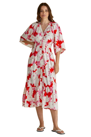 Woman wearing a red and white floral dress against a beige background