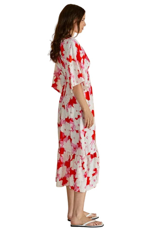 Woman wearing a red and white floral dress against a beige background