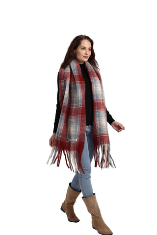 Woman wearing a plaid scarf, black top, blue jeans, and brown boots on a white background
