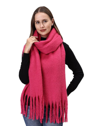 Woman wearing a bright pink scarf with tassels on a light gray background