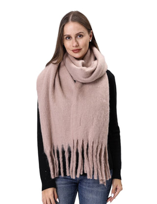 Woman wearing a beige scarf with fringe on a plain background