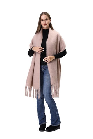 Woman wearing a beige scarf, black top, blue jeans, and black shoes on a white background