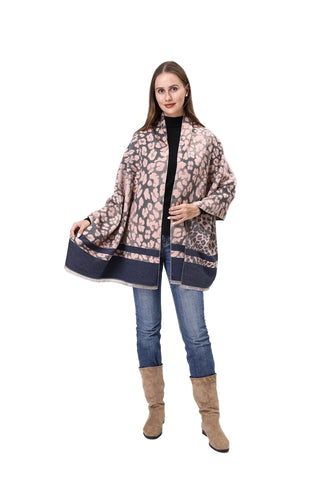 Woman wearing a patterned shawl over a black top and jeans, standing against a white background