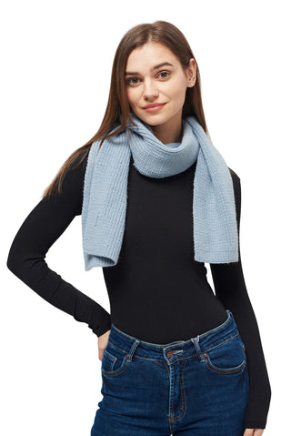 Woman wearing a light blue scarf, black long-sleeve top, and blue jeans on a white background