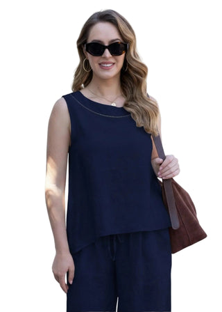 Woman wearing a navy blue outfit with sunglasses and a brown bag on a white background