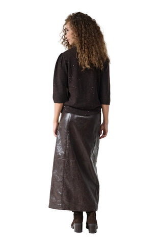 A model is shown from the back wearing a dark brown knit sweater and a dark brown faux-leather midi skirt, paired with dark brown boots, against a plain white studio background.
