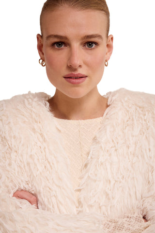 Woman wearing a textured white sweater against a plain background