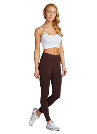 Woman wearing a white crop top and brown leggings on a gray background