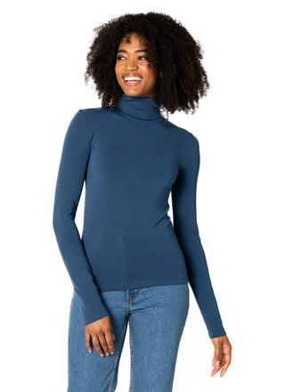 Woman wearing a blue turtleneck sweater and jeans on a white background
