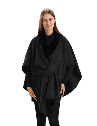 Woman wearing a black poncho against a white background