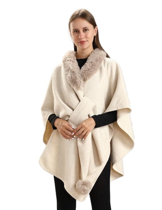 Woman wearing a cream-colored poncho with fur trim against a white background