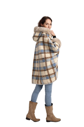Woman wearing a plaid coat with a fur-lined hood on a plain background