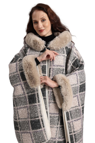 Woman wearing a checkered coat with fur trim on a plain background