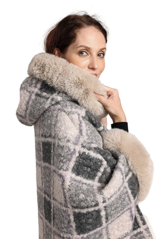 Woman wearing a checkered coat with fur trim on a gray background