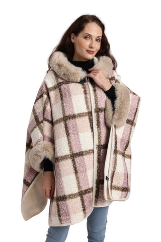 Woman wearing a checkered poncho with fur trim on a plain background