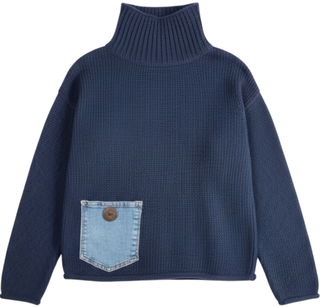 A navy blue ribbed knit turtleneck sweater with a light blue denim patch pocket on the front, featuring a single brown button closure.