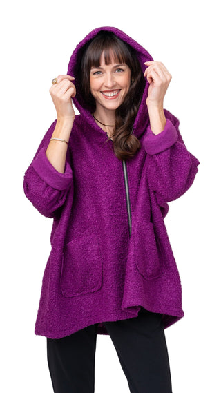 Woman wearing a purple hooded sweater against a white background