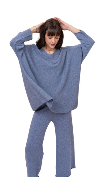 Woman wearing a blue poncho and pants on a white background