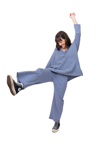 Person wearing a blue outfit with wide-leg pants and a matching top, standing against a white background.