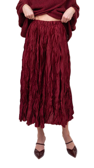 Person wearing a burgundy ruffled skirt on a white background