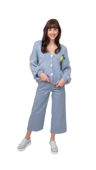 Woman wearing a light blue cardigan and pants on a white background