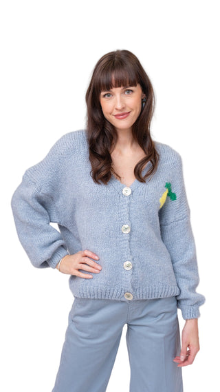 Woman wearing a light blue cardigan with a small design on a white background
