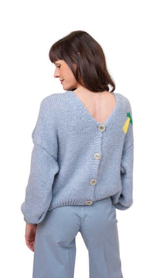 Woman wearing a light blue knitted cardigan with buttons on a plain background
