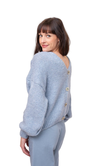 Woman wearing a light blue knitted cardigan with buttons on a white background