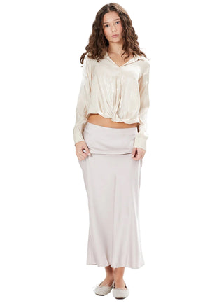 Woman wearing a cream blouse and white pants on a white background