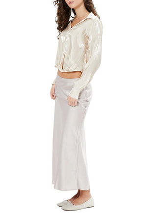Woman wearing a cream blouse and light gray pants on a white background