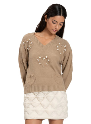 Woman wearing a beige sweater with decorative elements on a white background