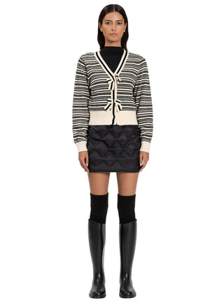 Woman wearing a striped cardigan, black skirt, and knee-high boots on a white background