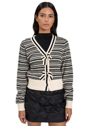 Woman wearing a black and white striped cardigan with a black quilted skirt on a white background