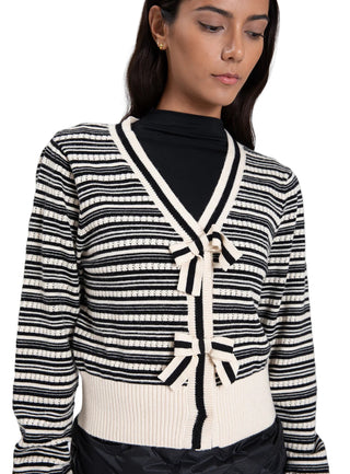 Woman wearing a black and white striped cardigan against a plain background