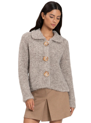 Woman wearing a gray textured jacket with decorative buttons on a white background