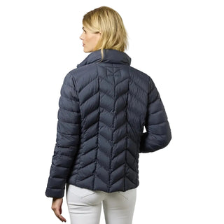 A woman shown from the back wearing a dark navy blue quilted puffer jacket and white pants, photographed against a neutral light gray studio background.