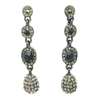 Pair of dangling earrings with black and clear gemstones on a white background