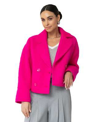 Woman wearing a bright pink coat in an elegant interior setting