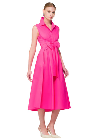 Woman wearing a bright pink dress with a floral arrangement in the background